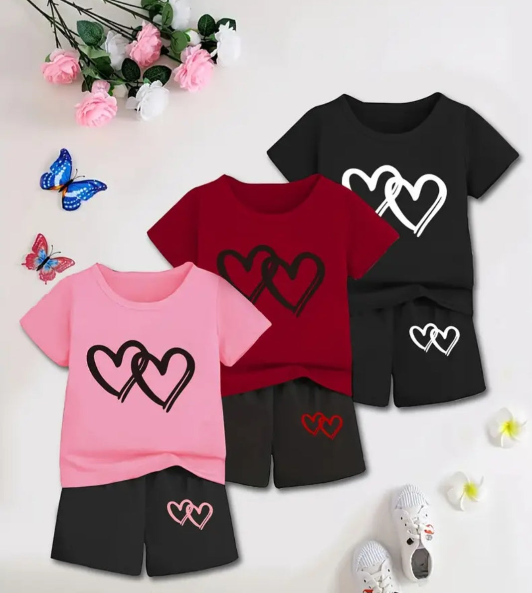 Girls' Summer Heart Outfit featuring a short sleeve T-shirt with a playful heart design and matching double heart print shorts in a vibrant color scheme, surrounded by decorative flowers and butterflies.